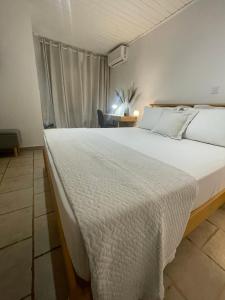 a bedroom with a large white bed and a chair at Cap Sounion Seafront Retreat in Sounio