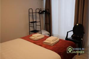 een slaapkamer met een bed met handdoeken erop bij Cantinho da Bea I in Angra do Heroísmo +12 foto's