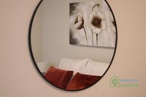 een spiegel in een kamer met een bed en bloemen bij Cantinho da Bea I in Angra do Heroísmo