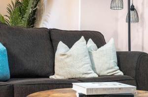 ein braunes Sofa mit weißen Kissen und einem Tisch in der Unterkunft The Arizona 2BR Pet-Friendly Suite Calgary SE in Calgary