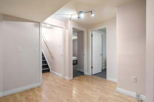 ein leeres Zimmer mit weißen Wänden und Holzböden in der Unterkunft The Arizona 2BR Pet-Friendly Suite Calgary SE in Calgary