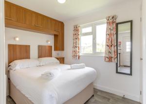 a bedroom with a large white bed and a window at Meadow Lakes Holiday Park in St Austell