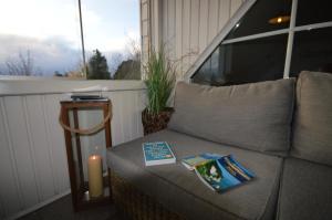 a couch with a book and a candle on a balcony at Komfortable Ferienwohnung In Waase Mit Garten in Ummanz