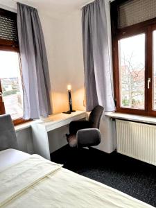 a bedroom with a chair and a bed and windows at Hotel Lamm in Pforzheim