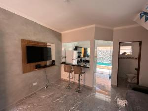 uma sala de estar com uma televisão e um balcão com duas cadeiras em Casa de condomínio com piscina e churrasqueira em São Paulo