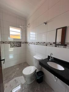 um banheiro com vaso sanitário e pia em Casa de condomínio com piscina e churrasqueira em São Paulo