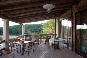 a patio with tables and chairs and a large window at Agriturismo Monte degli Aromi in Villaga