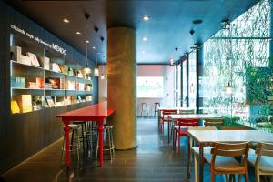 un restaurante con mesas y sillas rojas y ventanas en citizenM New York Times Square, en Nueva York