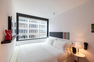 Un dormitorio con una cama blanca y una ventana grande. en citizenM New York Times Square, en Nueva York 26 fotos más