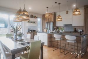a kitchen with white cabinets and a table and chairs at gîte chez julio in Sainte-Flavie