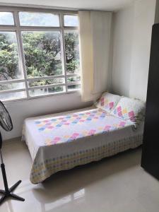 Bett in einem Zimmer mit zwei Fenstern in der Unterkunft Apartaestudios centro ibagué in Ibagué