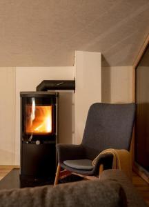 uma sala de estar com uma cadeira e um forno em Bijou Biobergün em Bergün