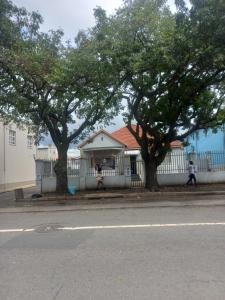 a house with two trees in front of a fence at JH Guest house in Durban