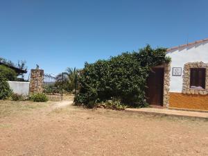 a house with a large bush next to a building at El Chorrillo in Alcuéscar
