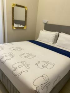 Una cama con un edredón blanco y un espejo. en JH Guest house, en Durban