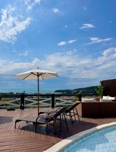 a patio with an umbrella and chairs next to a pool at Pousada Bella vista in Búzios