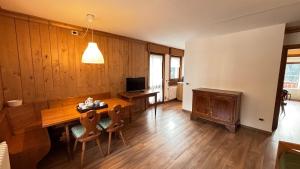 ein Wohnzimmer mit einem Holztisch und einem TV in der Unterkunft Appartamento panoramico al 2 Piano in San Vito di Cadore
