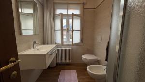 ein Badezimmer mit Waschbecken und Toilette und einem Fenster in der Unterkunft Appartamento panoramico al 2 Piano in San Vito di Cadore + 9 Fotos