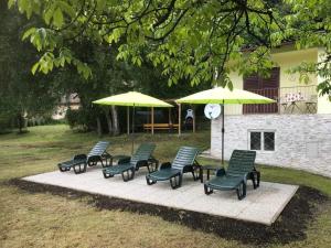 un groupe de chaises et de parasols sur une terrasse dans l'établissement Ferienhaus In Steindorf Am Ossiacher See, à Steindorf am Ossiacher See