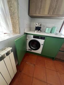 a kitchen with a washing machine in a green cabinet at Casa dos Assentos in Quintiães