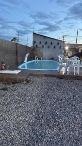 a swimming pool in a backyard with white chairs at Pousada novo mundo in Paulista