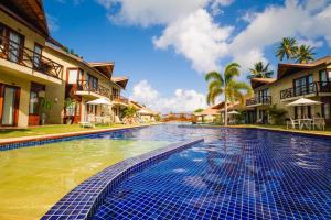 a swimming pool in a resort with palm trees and buildings at Pousada novo mundo in Paulista