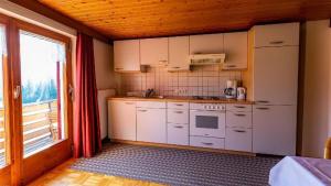 a kitchen with white appliances and a large window at Ferienwohnung Haus Kipfen In Sibratsgfäll in Sibratsgfäll