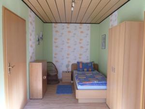 ein kleines Schlafzimmer mit einem Bett und einer Wand in der Unterkunft Orpington in Dreisbach