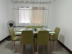 uma mesa de jantar com cadeiras verdes e uma janela em Soglad Transient House em San Juan