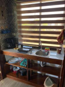une cuisine avec un évier et une fenêtre avec des stores dans l'établissement Cabina Entre Playas, à Huacas 8 autres photos