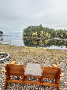 a wooden bench sitting next to a body of water at NORTHWEST EAGLE NEST LIMIT 9 home in East Sebago