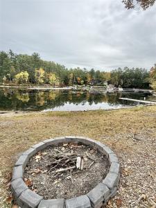 a fire pit in a field next to a lake at NORTHWEST EAGLE NEST LIMIT 9 home in East Sebago
