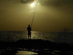 a man standing on a rock in the water fishing at tasurft house imsoune in Imsouane