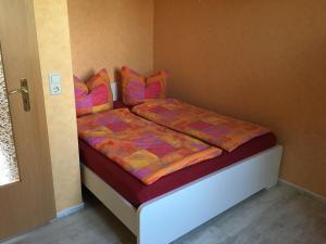 ein kleines Schlafzimmer mit einem Bett mit bunten Decken und Kissen in der Unterkunft Gemütliches Ferienhaus in Godow mit Großer Terrasse in Kargow