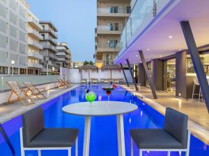 ein Tisch mit zwei Stühlen und einem Glas Wein auf einem Swimmingpool in der Unterkunft Mercure Rhodes Alexia Hotel & Spa in Rhodos (Stadt)