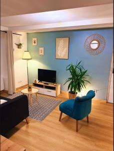 a living room with a tv and a blue wall at Le romantique du centre-ville Dole in Dole