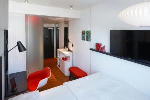 a bedroom with a bed with a tv and red chairs at citizenM San Francisco Union Square in San Francisco