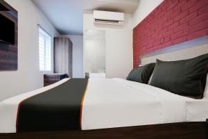 a bedroom with a white bed with a red brick wall at Super Collection O Kalinga Bapuji Nagar in Bhubaneshwar