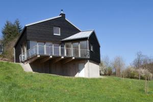 a black house on top of a grassy hill at Kleines Vulkaneifelhaus in Schutz