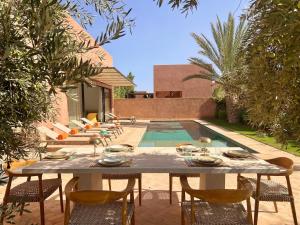 a dining table and chairs in front of a pool at Villa AYA - Moderne & Chic in Sraghna