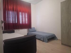 a bedroom with a bed and a window with red curtains at Apartament Sos Alexandriei Bragadiru in Bragadiru