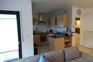 ein Wohnzimmer mit Couch und Küche in der Unterkunft Barrierefreie Ferienwohnung mit Terrasse und überdachtem Grillplatz und Garten zur gemeinschaftlichen Nutzung in Osterbrücken