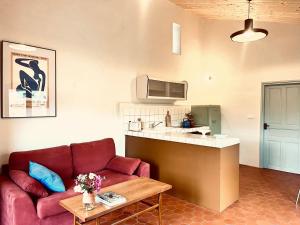 a living room with a red couch and a kitchen at Mas Saint Michel in Vivès