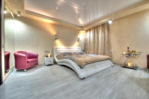 a bedroom with a large bed and a pink chair at Alex Hotel on Bogatyrsky in Saint Petersburg