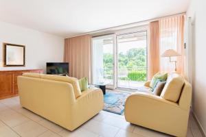 uma sala de estar com duas cadeiras amarelas e uma televisão em Golf Ranch, 1Er Stock em Ascona