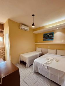 a hotel room with two beds and a fan at Pousada Praia Dos Encantos in Japaratinga