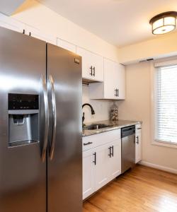 einen Kühlschrank aus Edelstahl in einer Küche mit weißen Schränken in der Unterkunft Latitude Adjustment in Virginia Beach