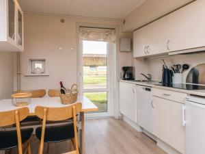 a kitchen with white cabinets and a table and chairs at 6 person holiday home in Rømø in Rømø Kirkeby
