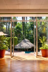 帕伦克Hotel Maya Palenque的通往露台的门敞开着，露台上撑着一把草伞。