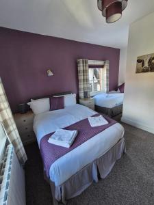 a bedroom with two beds and a purple wall at The Stokesay Inn in Craven Arms